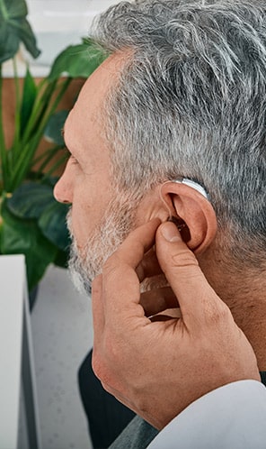 Man at his audiologist getting hearing aids adjusted
