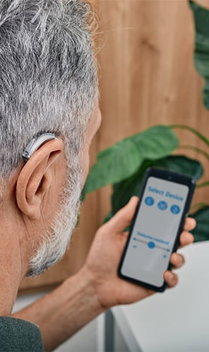 Man using hearing aids connected to his phone via Bluetooth