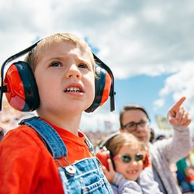 Young kid wearing hearing protection while watching a race